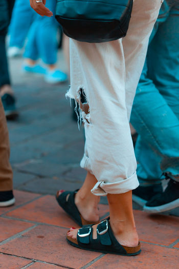 Low section of woman wearing torn pants while walking on street