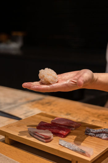 Cropped hand of woman holding food on table