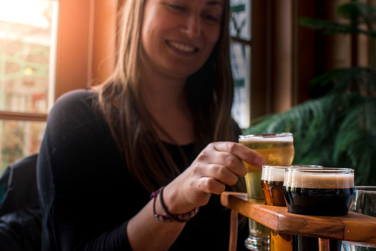 Young woman tasting craft beer at bar