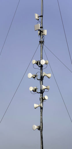 Microwave communication horns attached to a pole supported by guy wires against a clear sky