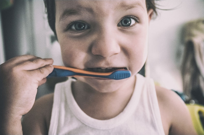 Close-up portrait of cute boy brushing teeth