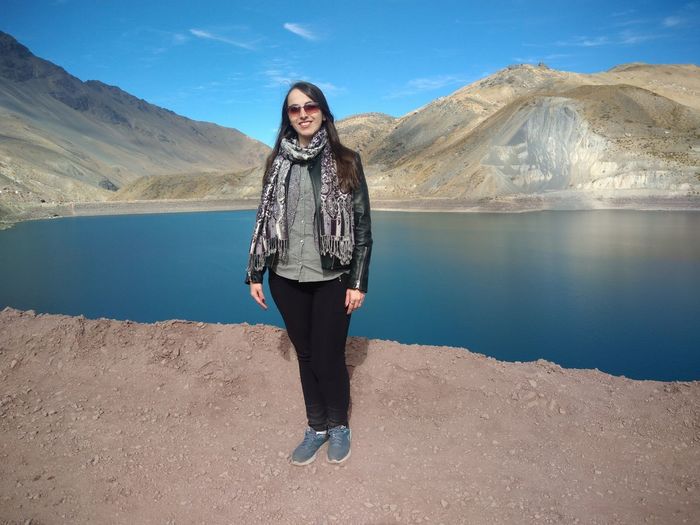 Portrait of smiling young woman standing on lake
