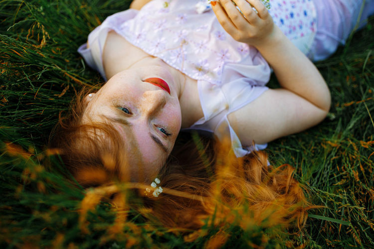 high angle view of young woman lying on grassy field