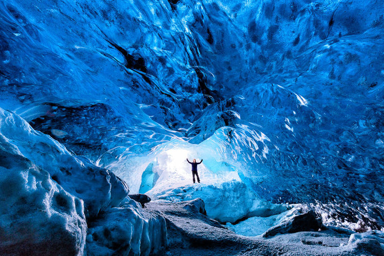 Excited person standing in ice cave