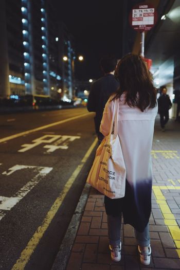 Rear view of women walking on road at night
