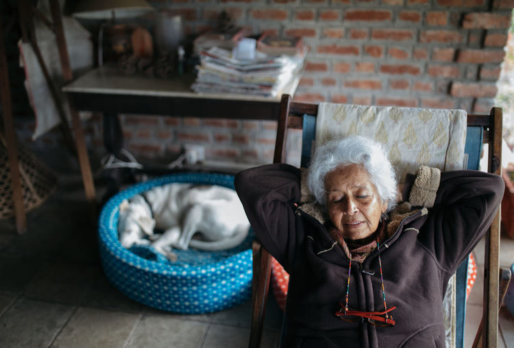 High angle view of senior woman relaxing on chair at home