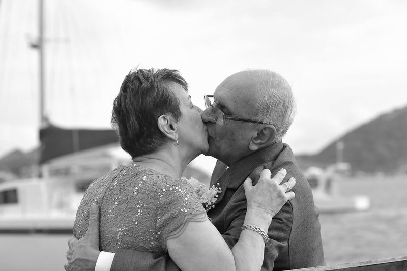 Close-up of senior couple kissing while standing against sky