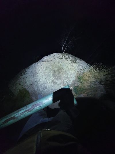Person holding umbrella on rock at night
