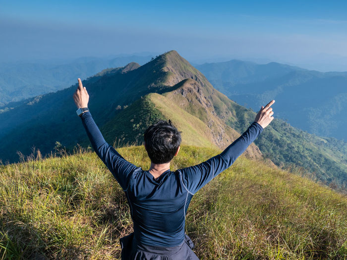 Rear view of woman with arms raised on mountain