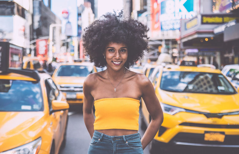 Portrait of confident young woman with afro hairstyle standing on city street