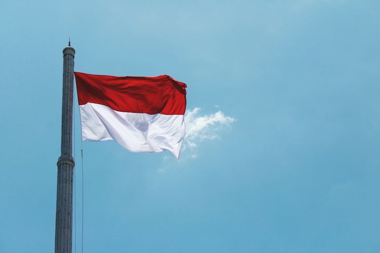 Low angle view of indonesian flag against blue sky