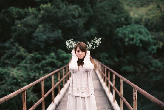 Portrait of a young woman standing on footbridge