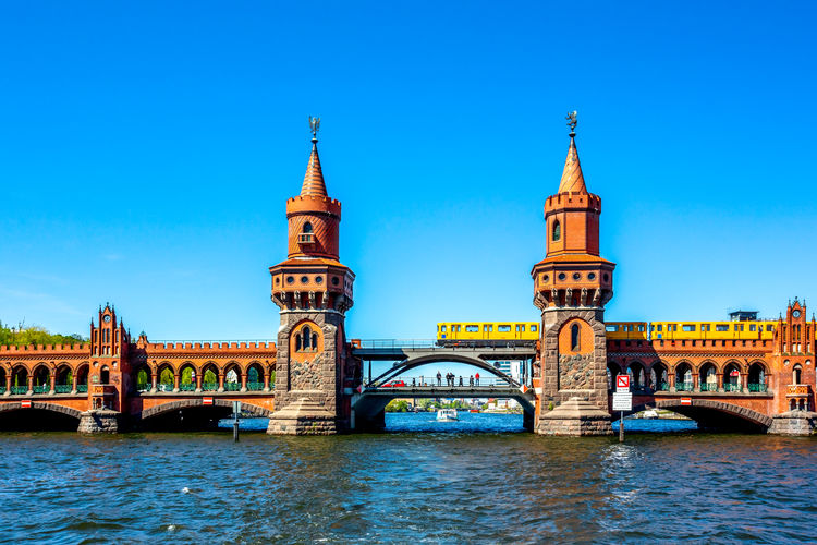 Arch bridge over river against blue sky