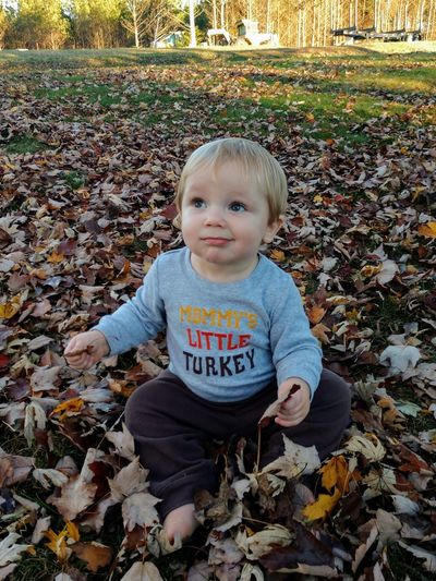 Portrait of boy with dry leaves during autumn