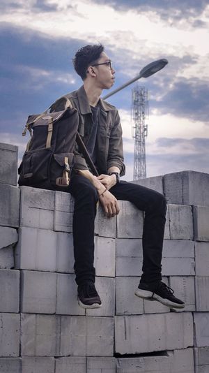 Full length of young man looking away against sky
