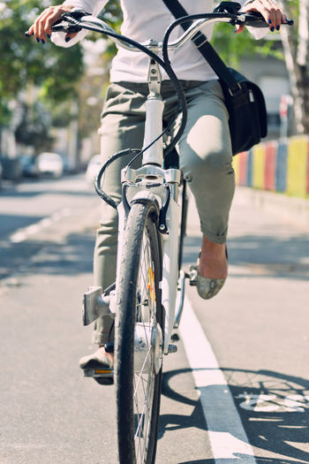 Low section of woman riding bicycle on road
