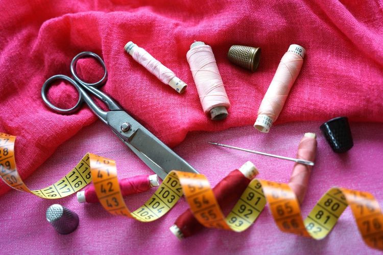 High angle view of sewing items on pink fabrics