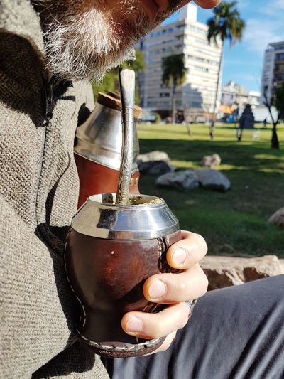 Midsection of man having yerba mate in city