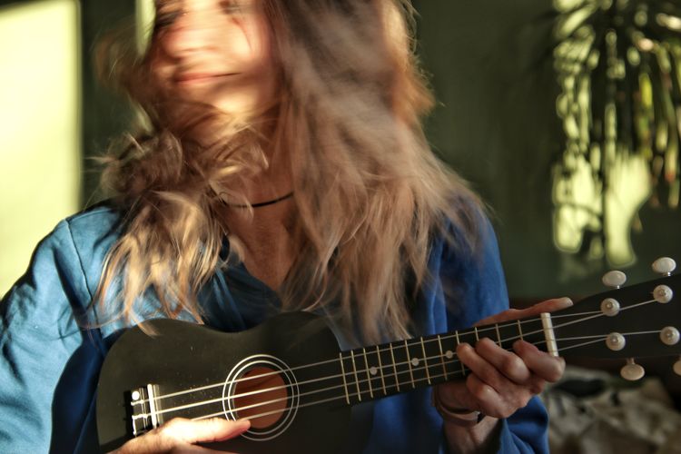 Midsection of woman playing guitar