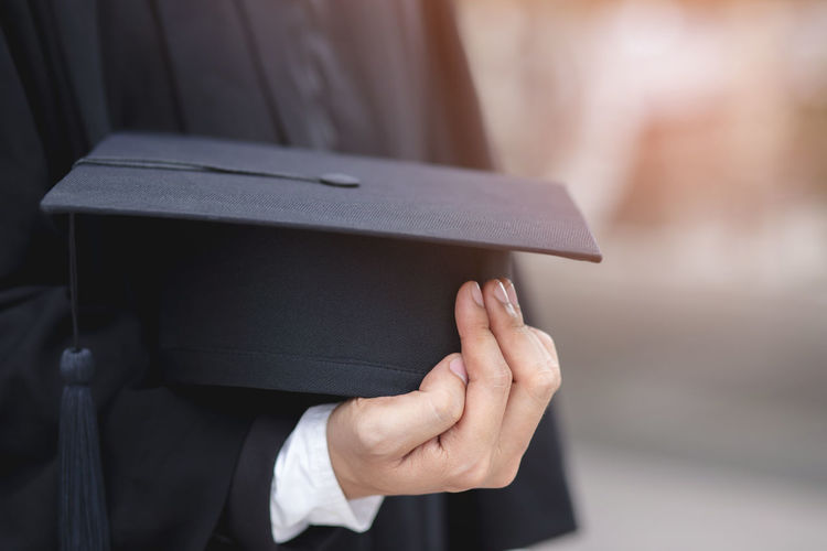 Midsection of student holding mortarboard