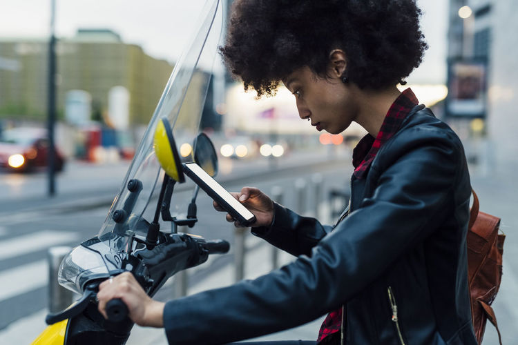 Woman using rental motor scooter through smart phone