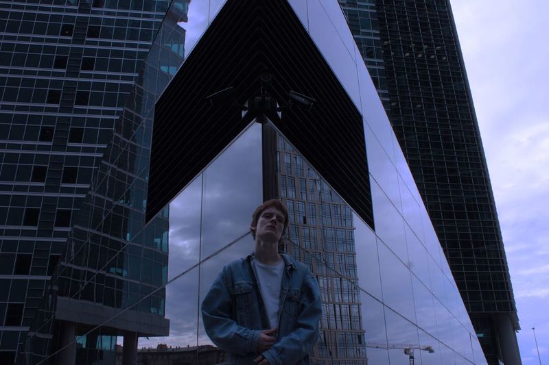 Low angle view of man standing against modern buildings
