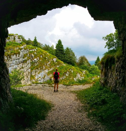 Full length of woman standing on grassy landscape viewed from inside a cave