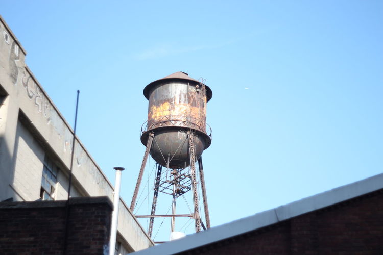Low angle view of water tower on building against clear sky
