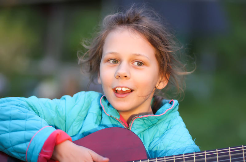 Cute girl playing guitar outdoors
