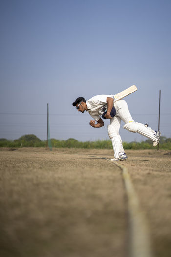 Full length of man exercising on field against clear sky