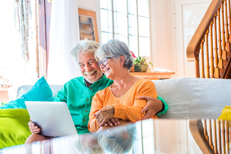 Smiling couple using laptop at home