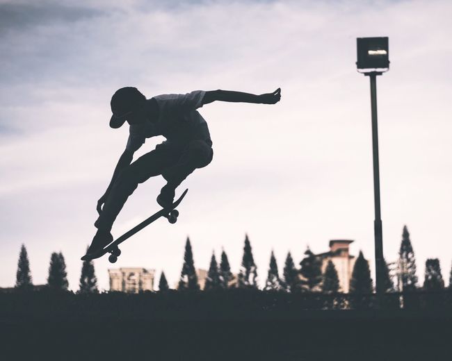 Skateboarder performing stunt against sky