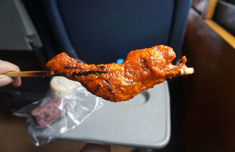 Cropped hand holding chicken in skewer