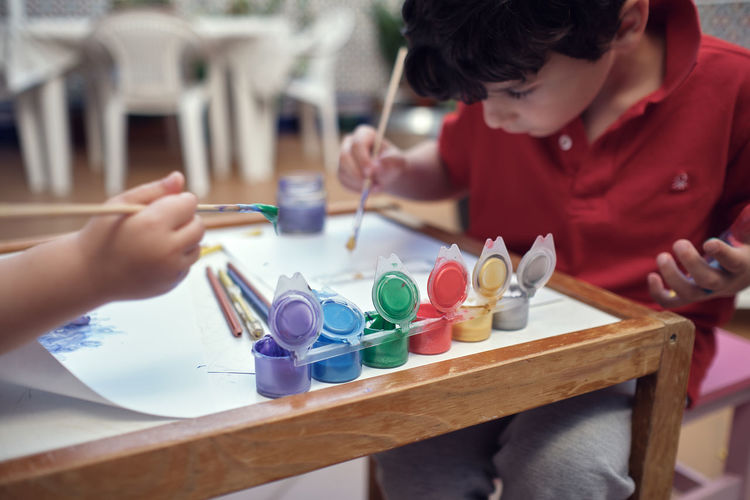 Children playing in an inner courtyard and painting with water paints