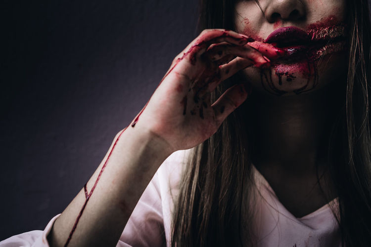 Midsection of young woman with halloween make-up against wall