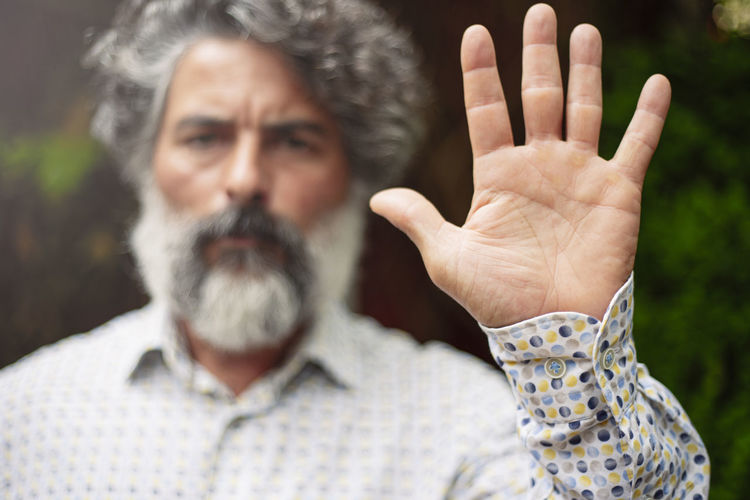 Bearded man in casual clothes making stop gesture with his hand person