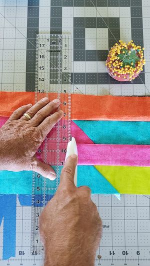Close-up of hand cutting multi colored paper with utility knife