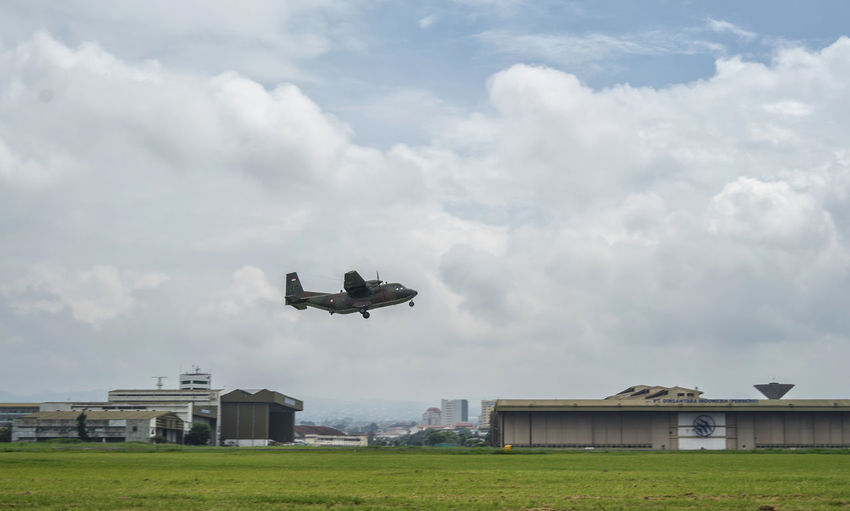 Airplane flying over field against sky
