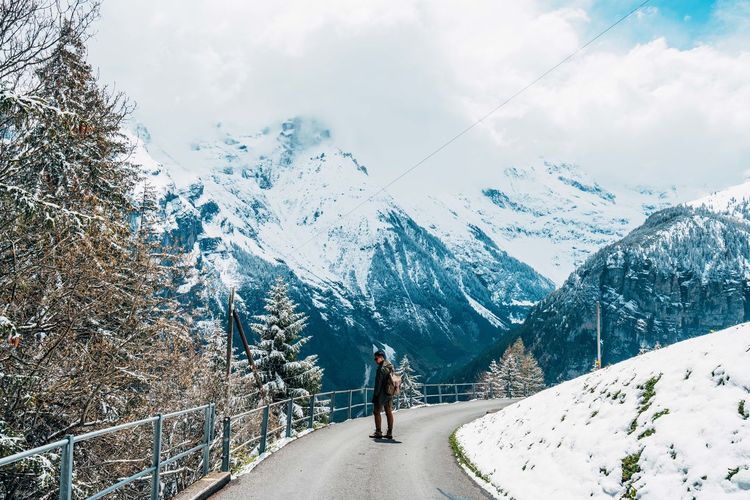 Man walking on road against snowcapped mountains