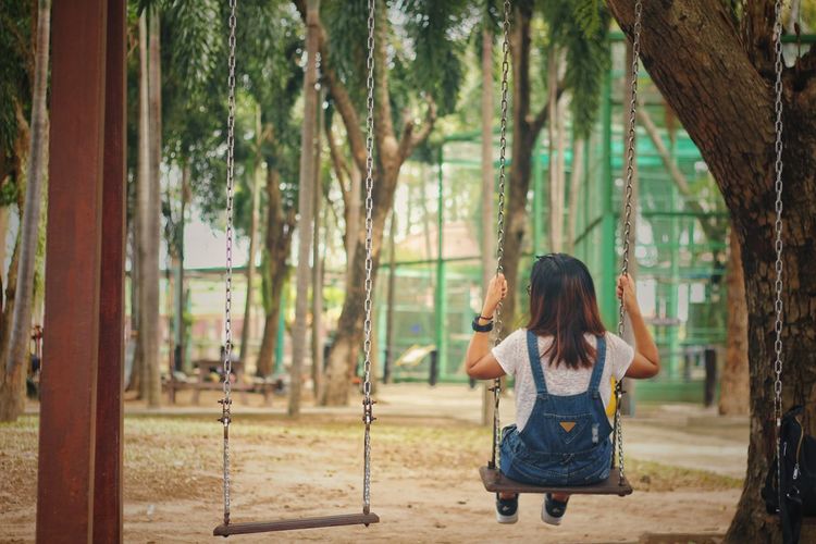 Rear view of girl swinging at playground