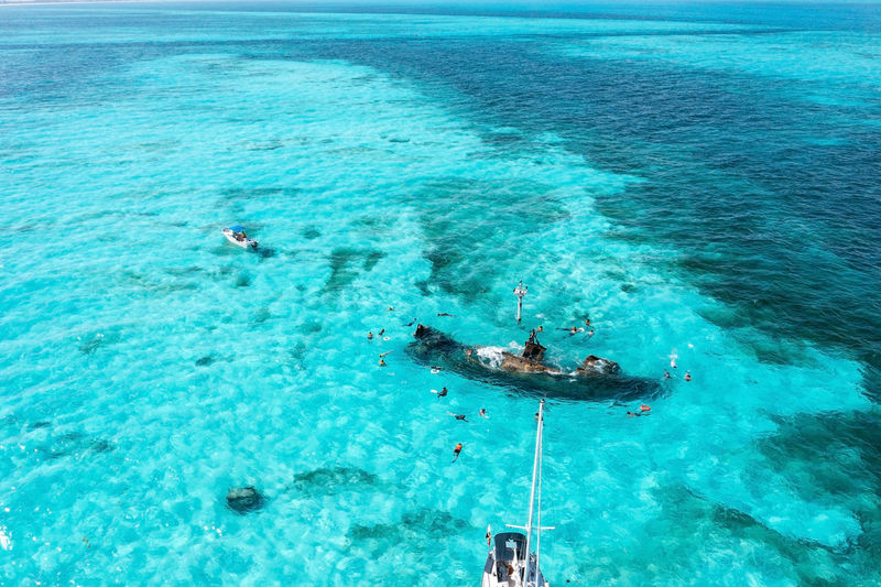 People snorkelling around the ship wreck near bahamas in the caribbean sea.