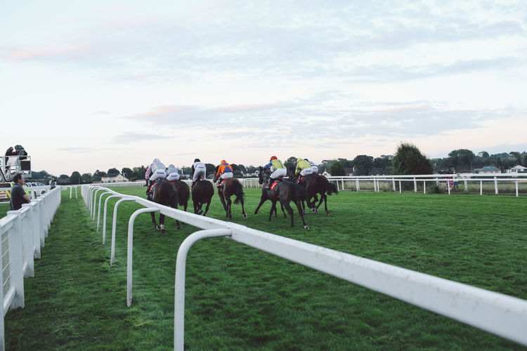 Jockeys riding horses at epsom downs racecourse against sky