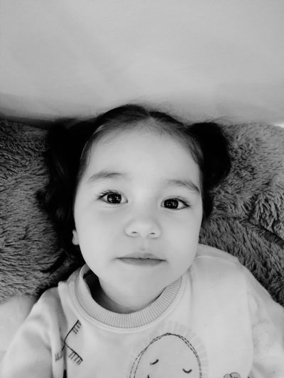 Portrait of cute baby lying on bed at home