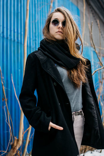 Portrait of young woman wearing warm clothing against corrugated iron