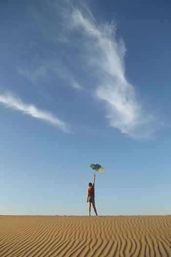 Full length of woman standing on desert against sky