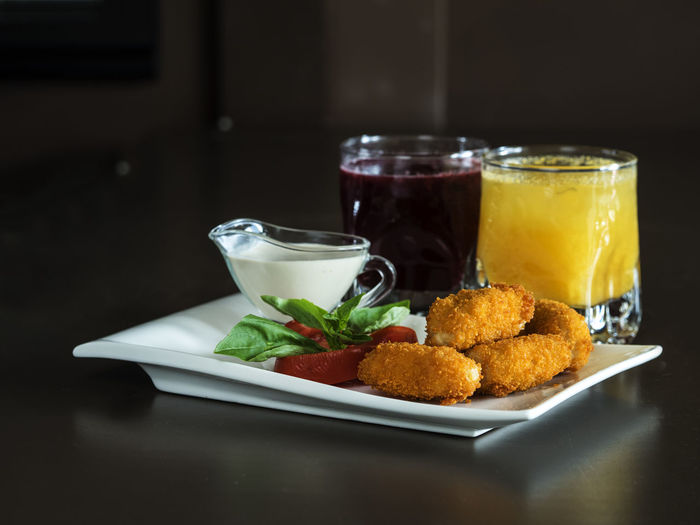 Chicken nuggets in plate by drinks served on table