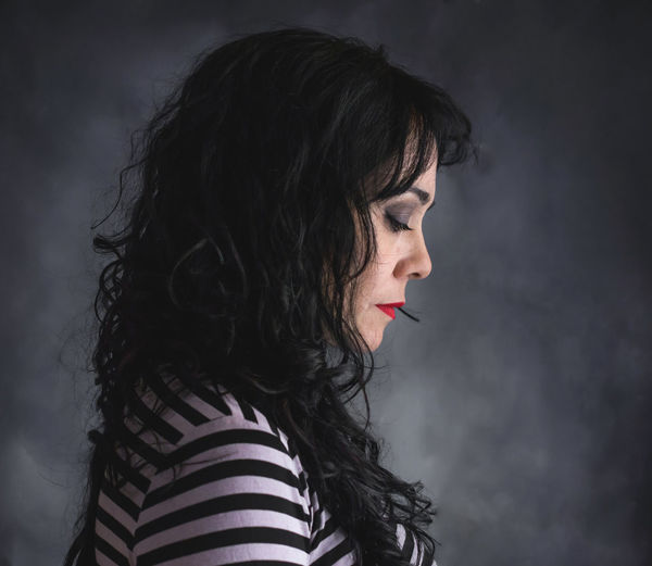 Side view of mature woman looking down against wall