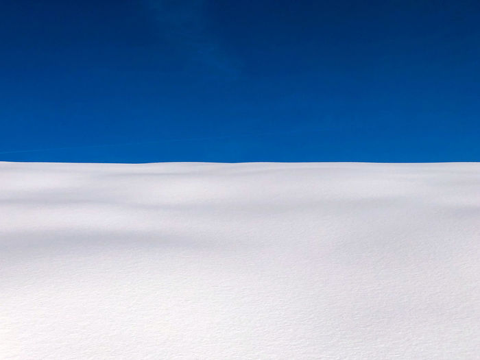 Scenic view of snowcapped landscape against blue sky