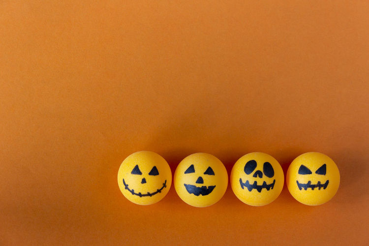Directly above shot of jack o lantern balls on orange background