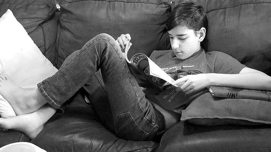 Rear view of boy looking at camera while sitting on sofa